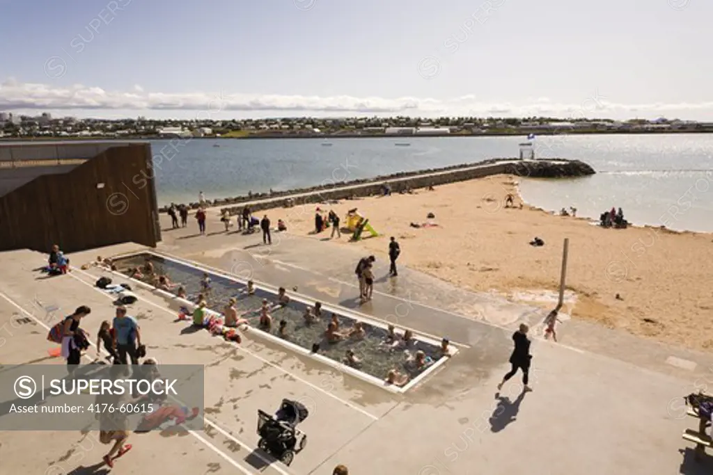 People enjoying the day at Nautholsvik beach, Reykjavik Iceland.  The water in the lagoon is heated using geothermal water.