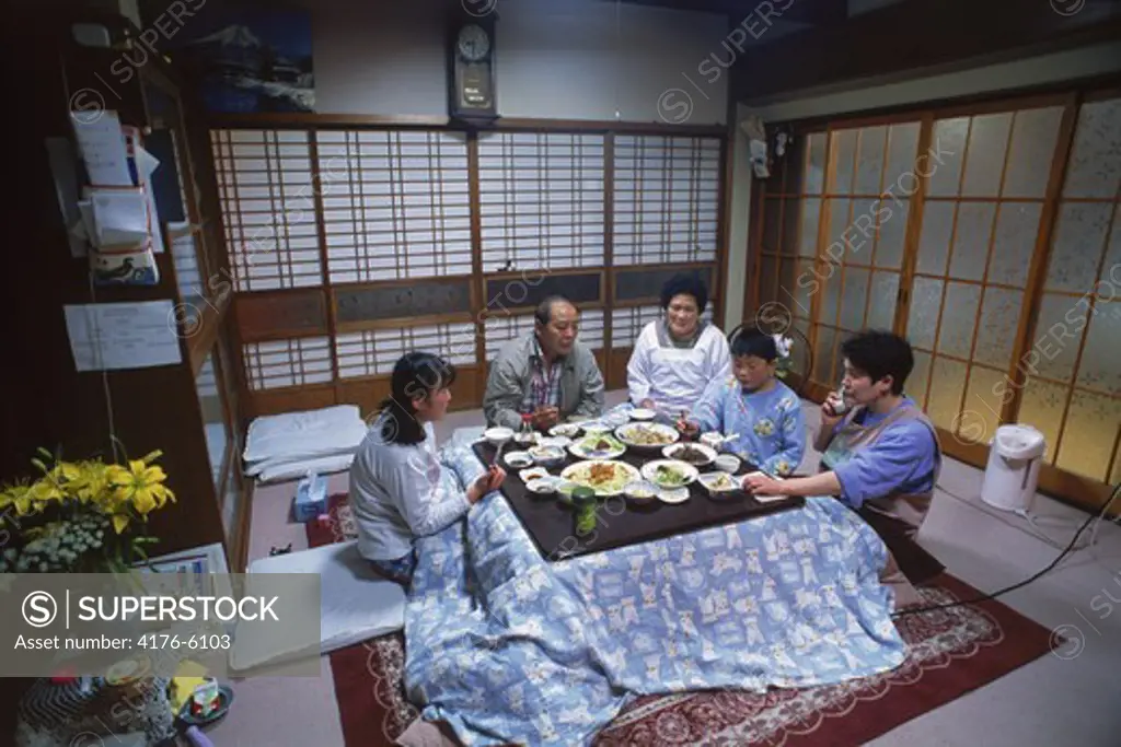 Family eating dinner in main room of  typical Japanese home in Kyoto