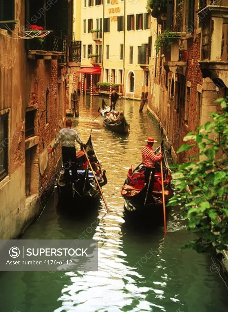 Gondolas filled with tourists passing on narrow canals in Venice