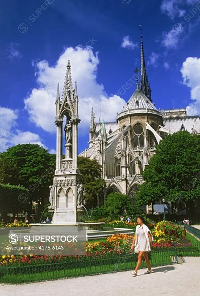Woman passing gardens on Ile de la Cite with Notre Dame in Paris