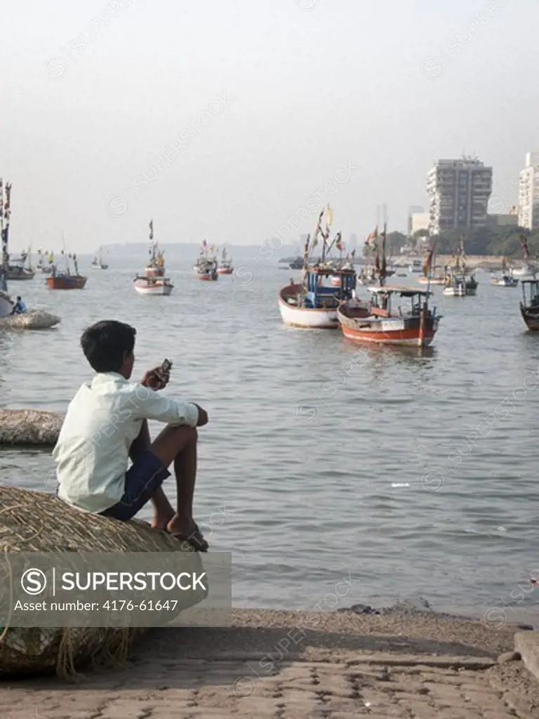 Boy by the ocean using his phone, Mumbai, India