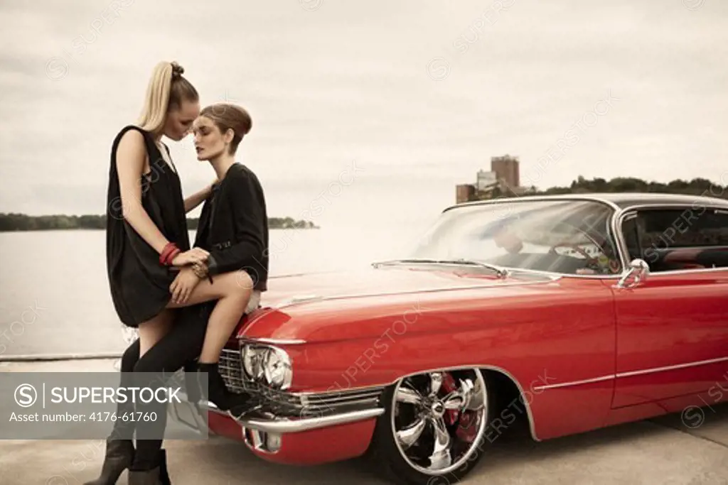Two women kissing infront of car. Stockholm. Sweden