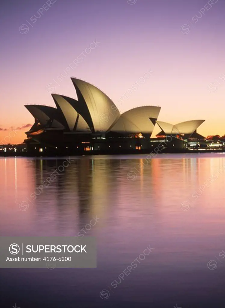Sydney Opera House relecting off calm harbor waters at sunrise