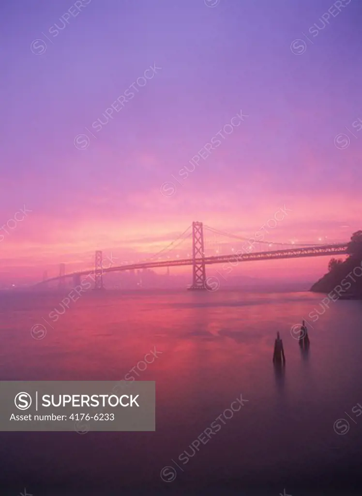 Oakland Bay Bridge under crimson sunset skies