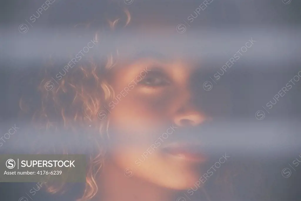 Latin American woman looking through bedroom curtains
