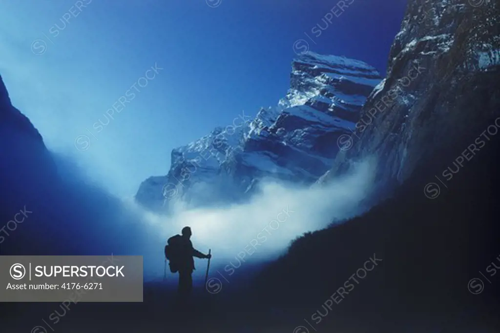 Lone trekker above clouds and below Himalayan peaks of Annapurnas in Nepal