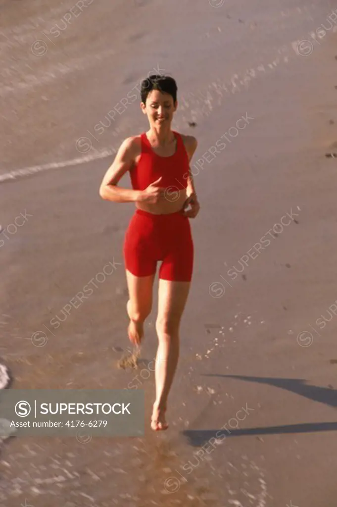 Woman in red running along sandy shore