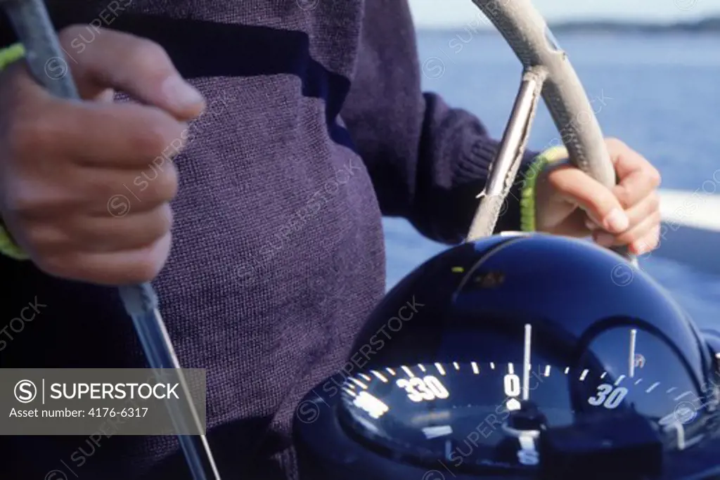 Man at helm with compass and hands on wheel