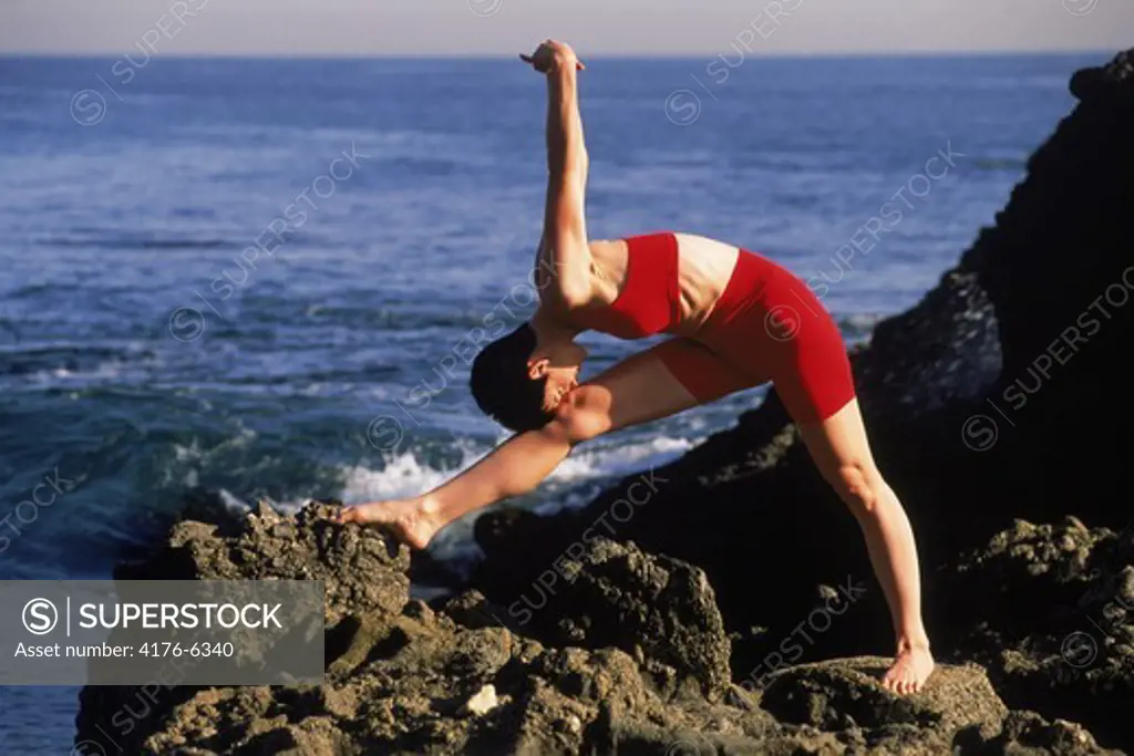 Woman stretching and exercising on rocky shore