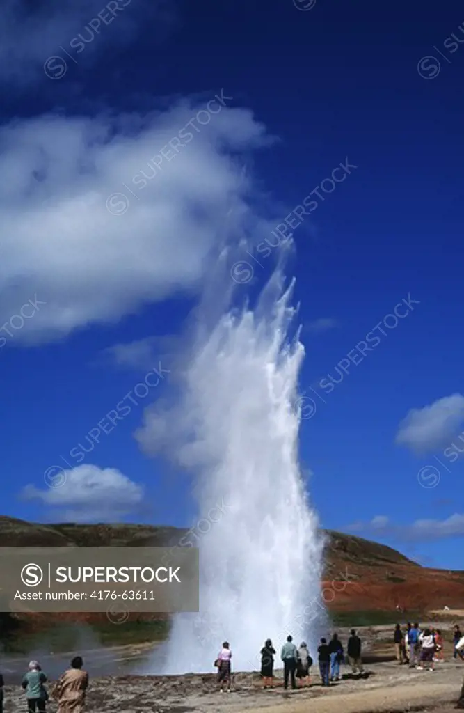 Tourists looking at erupting geyser