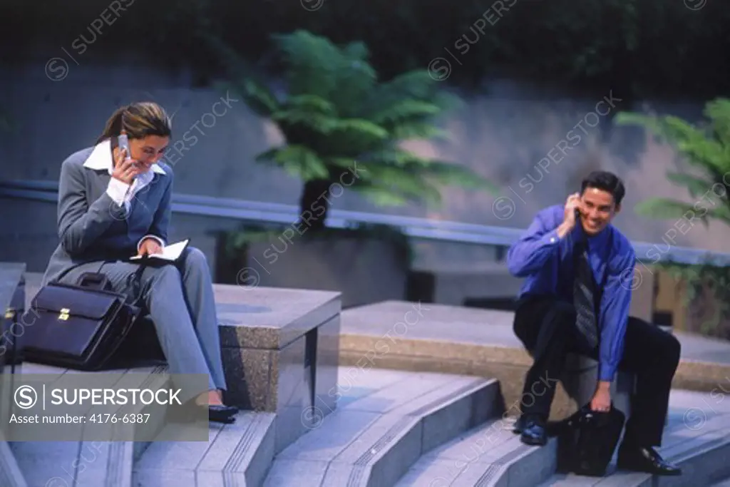 Business people with cellphones and briefcases on steps in downtown Los Angeles