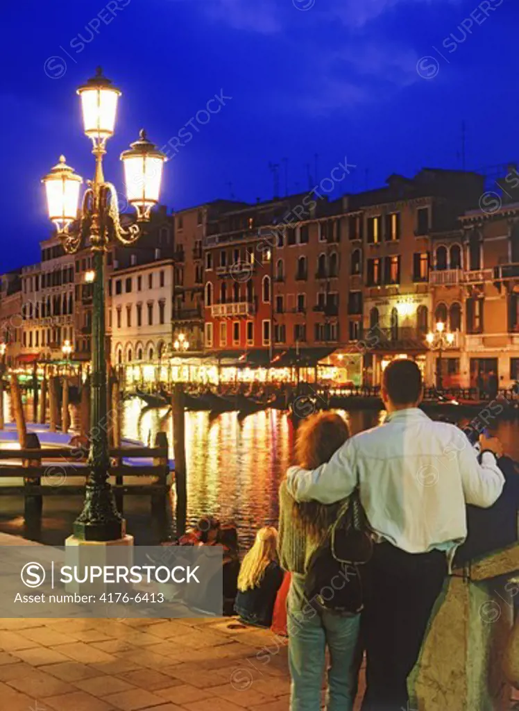 Couple next to Rialto Bridge on Grand Canal at night in Venice