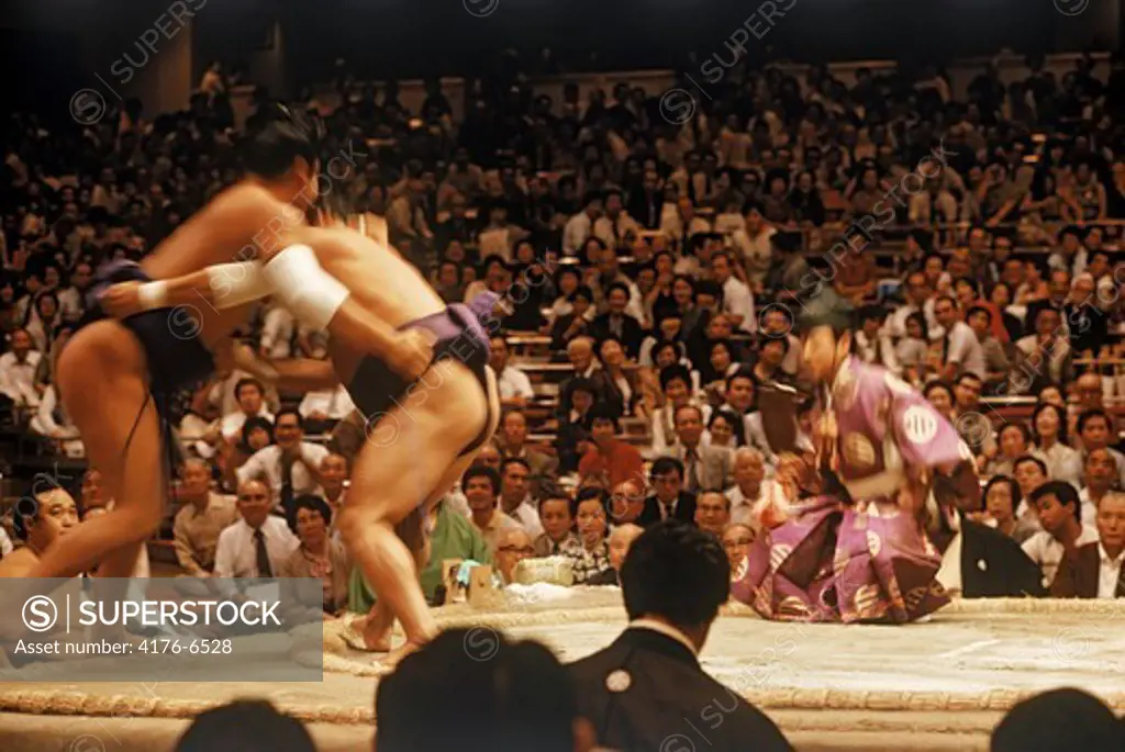 Sumo wrestlers in loincloth and sash or mawashi fighting in ring or dohyo