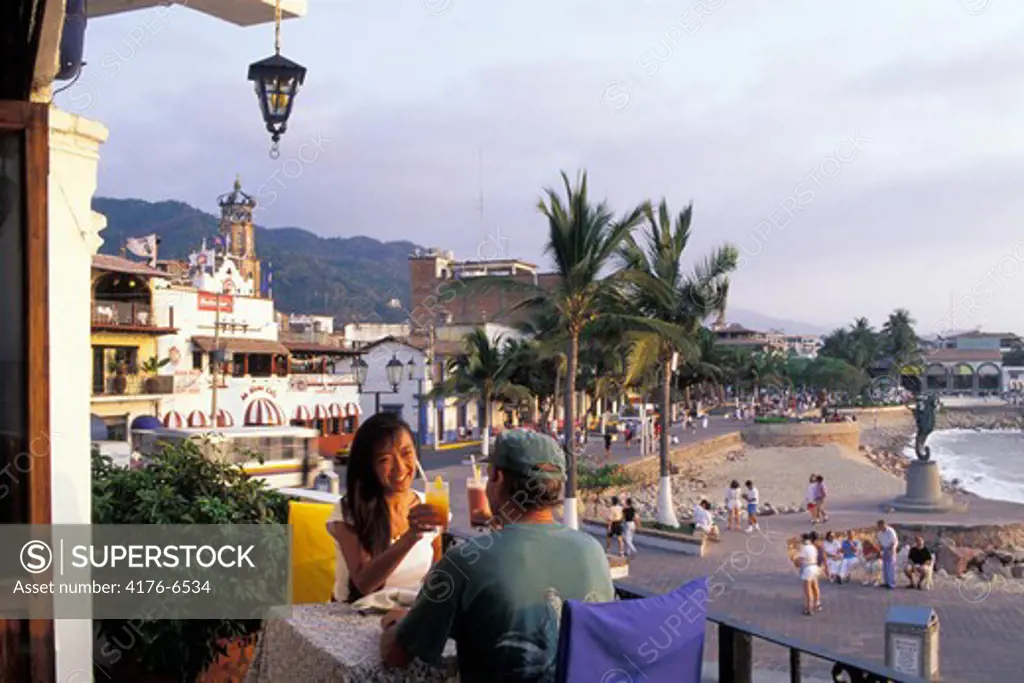 Couple having sunset drinks at oceanfront restaurant in Puerto Vallarta Mexico