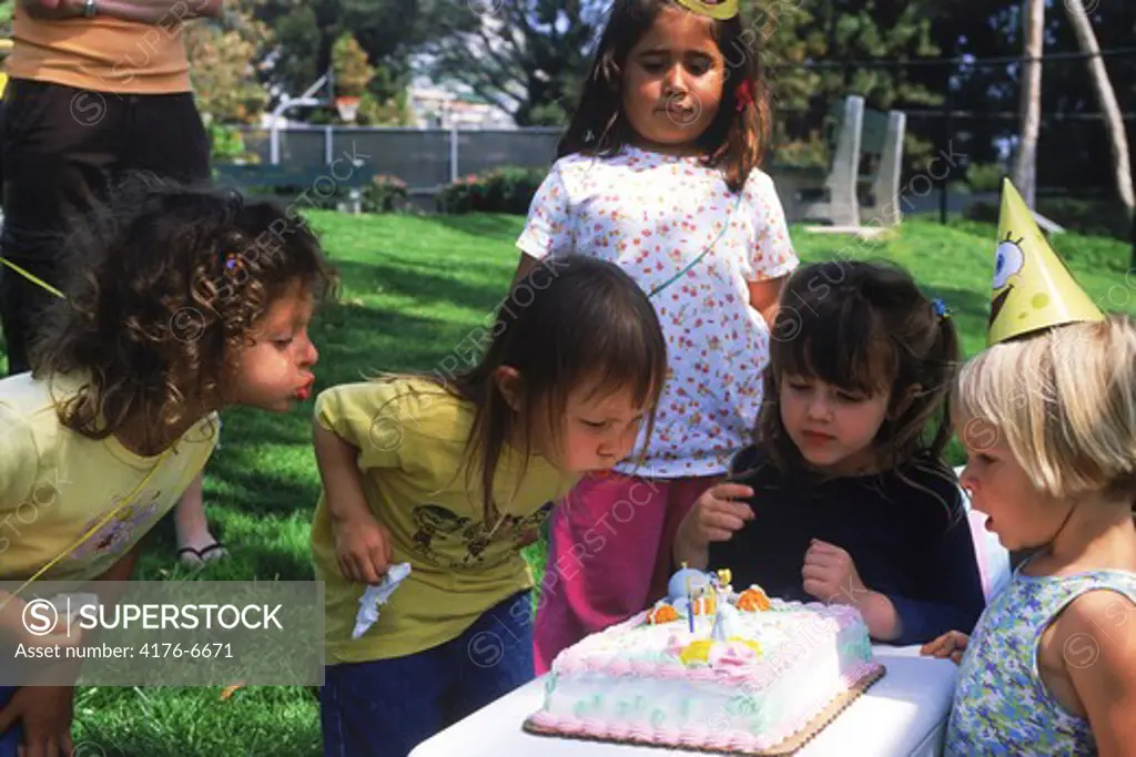 Kids at birthday party blowing out candles