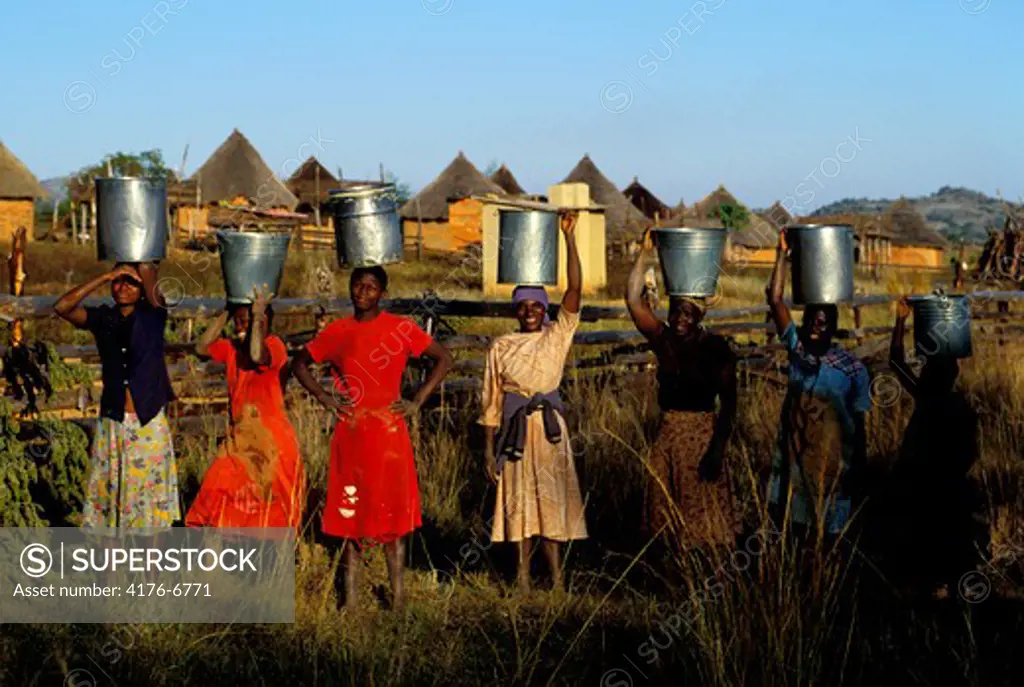 Young women porting buckets of water into rural Zimbabwe village