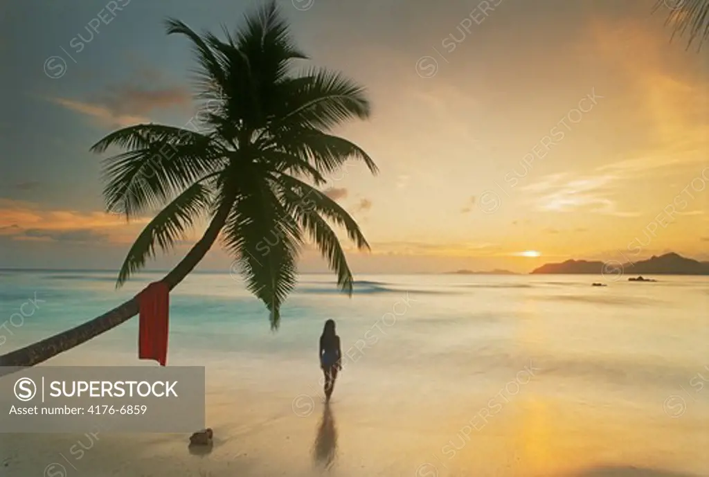 Woman standing at Anse Severe on La Digue with Praslin Island on horizon