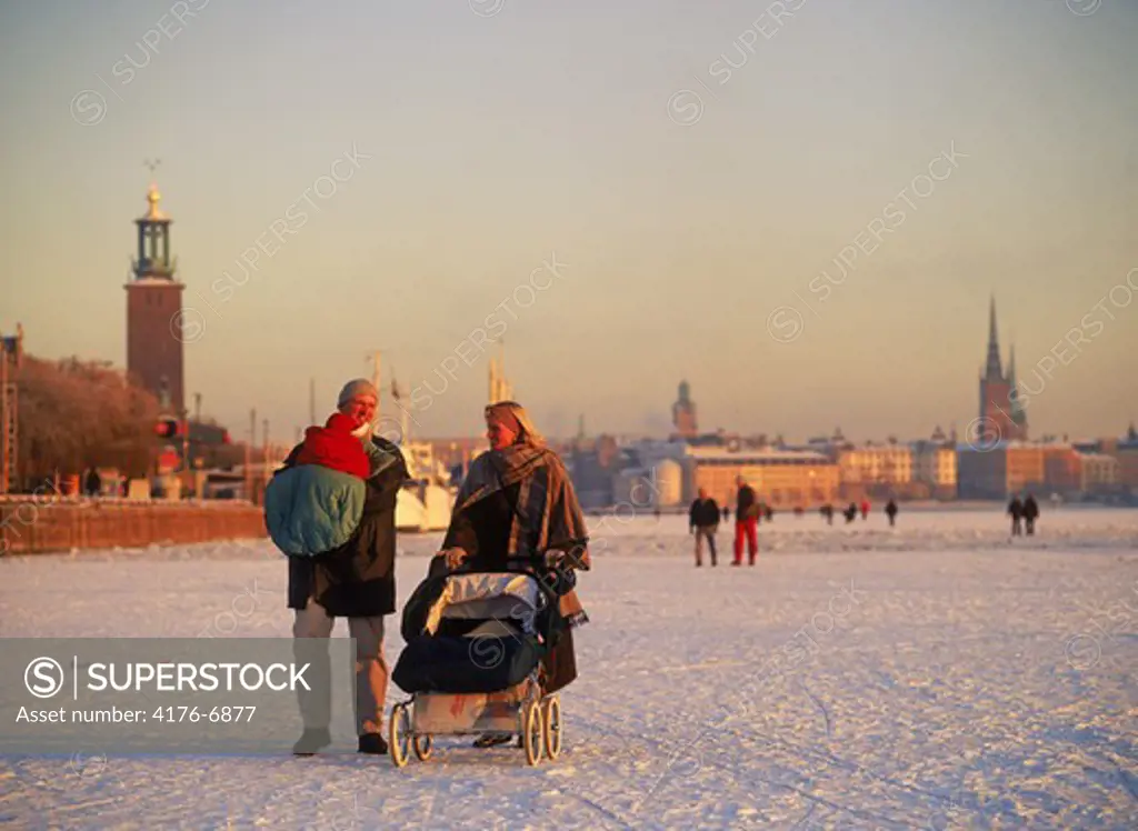 Family pushing baby carriage across frozen Riddarfjarden in Stockholm winter