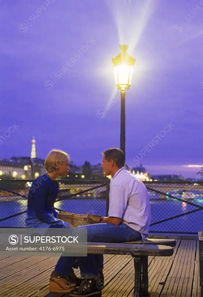 Young couple on Pont des Arts at night in Paris