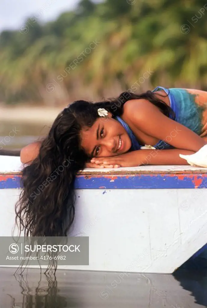 Polynesian girl laying on outrigger canoe on Aitutaki beach