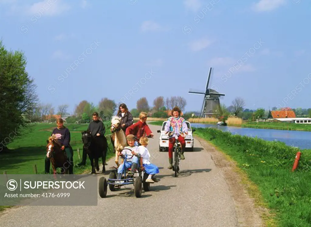 Kids on road in Schermerland with canal and windmill in Holland