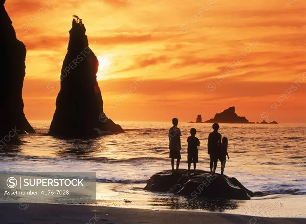 Four kids standing on rock at sunset with seastacks at Olympic National Park on Olympic Peninsula in Washington