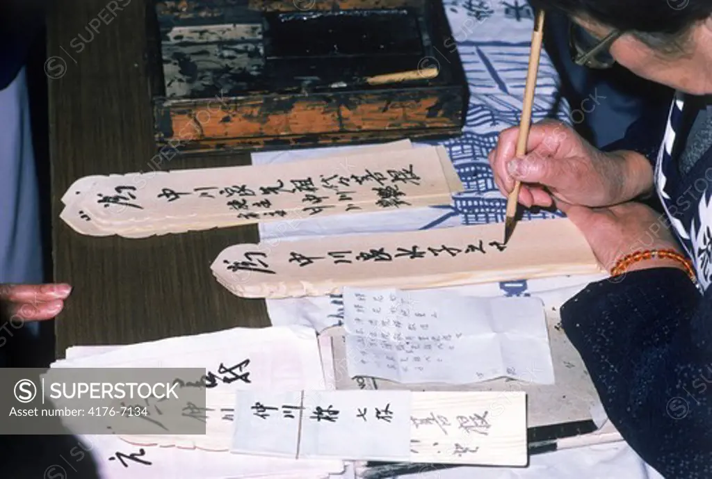 Writing prayers on toba sticks outside Buddhist temple in Japan