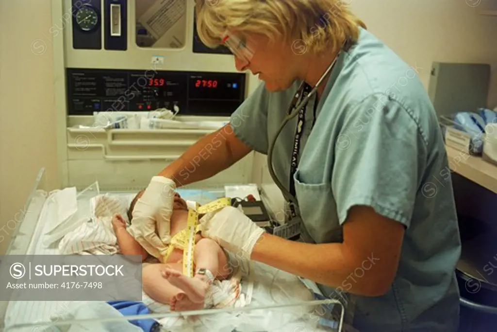 Nurse taking measurements of newborn baby