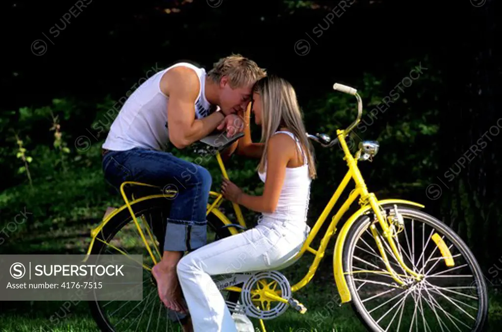 Young couple sitting face to face on yellow bike