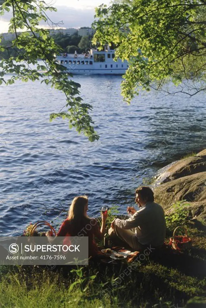 Couple having picnic at sunset on waterway in Stockholm