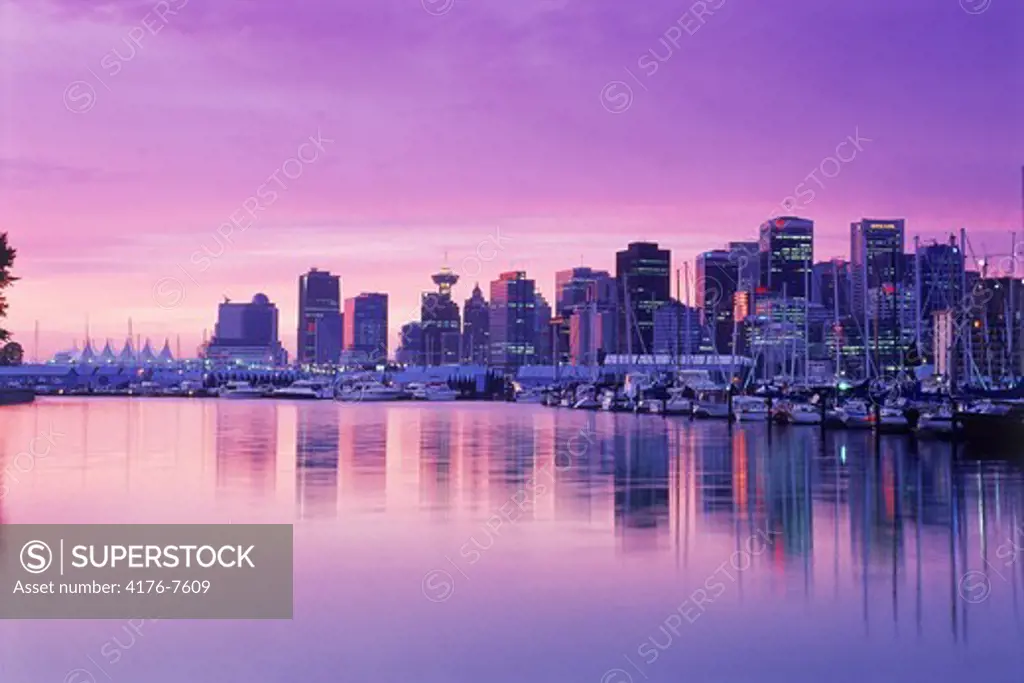 Mirror images of Vancouver skyline on harbor from Stanley Park at dawn