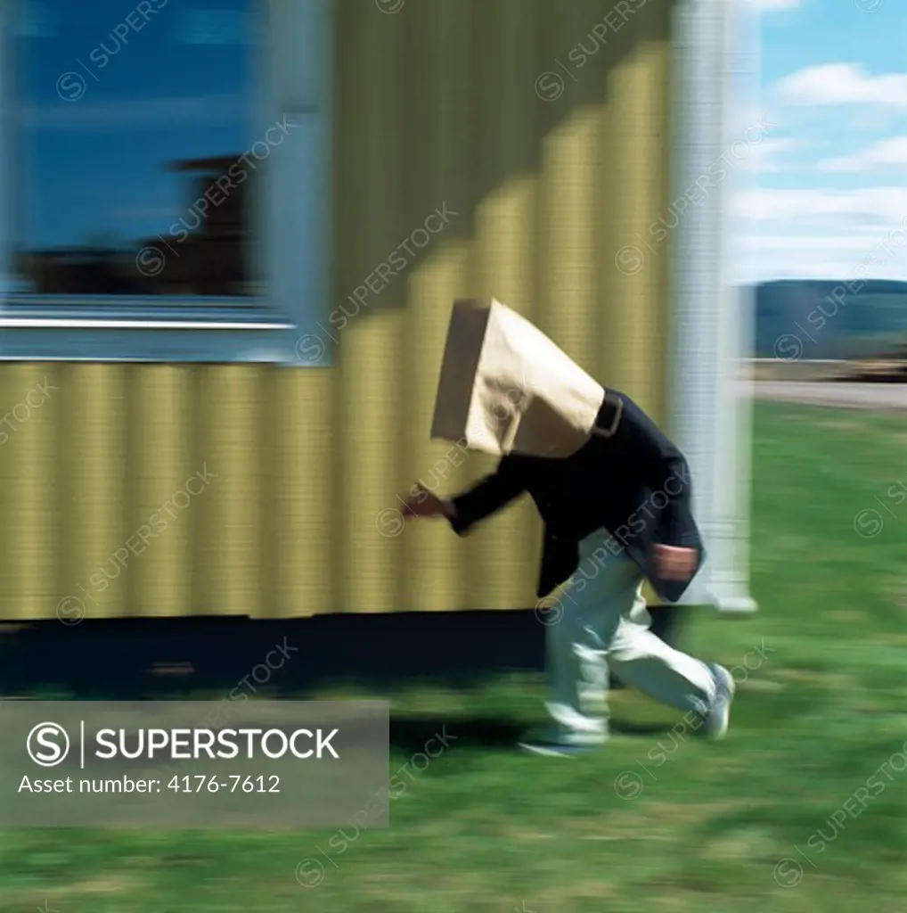 Side profile of a boy running with his face covered with a paper bag