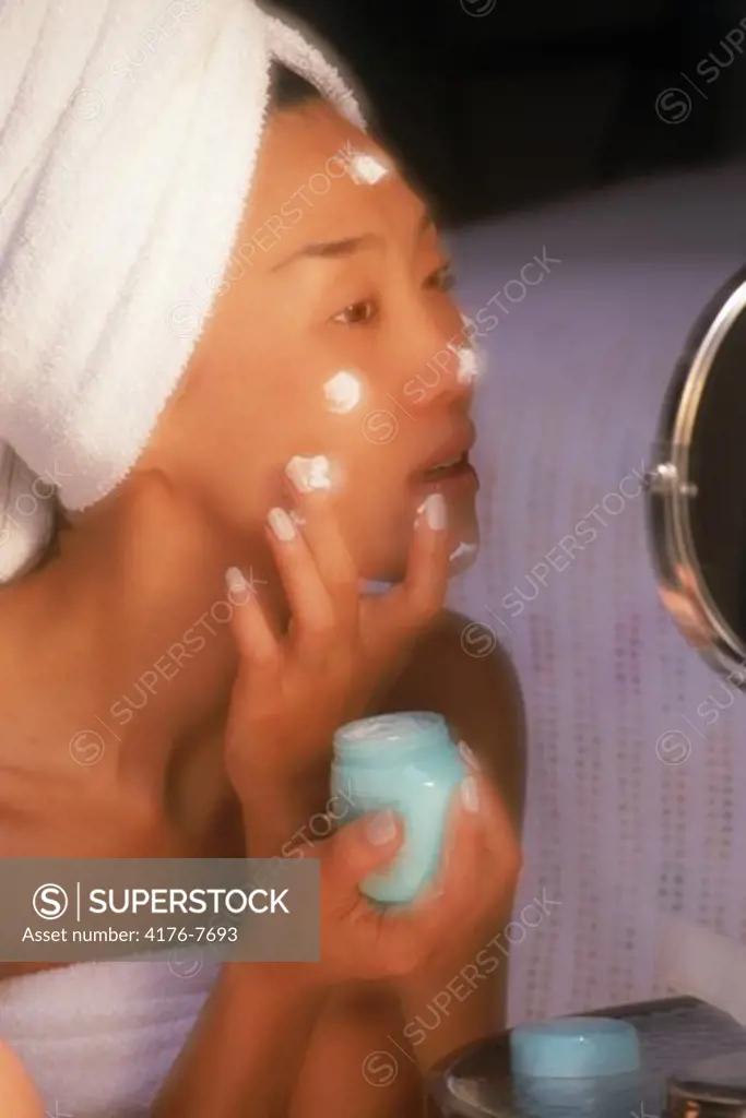 Asian woman applying moisture creme to face