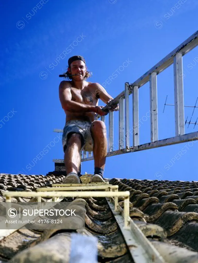 A man with a ladder on a roof