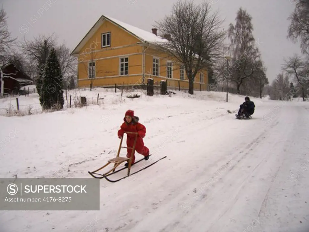 A child sledging through a rural area. Sweden