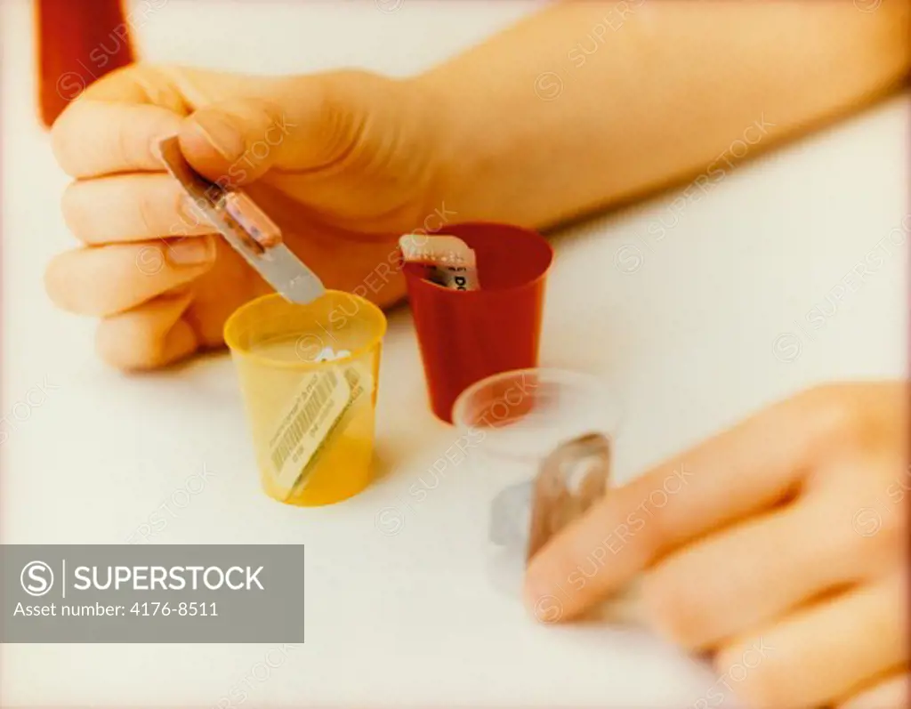 Close-up of a person's hand taking pills from a pillbox