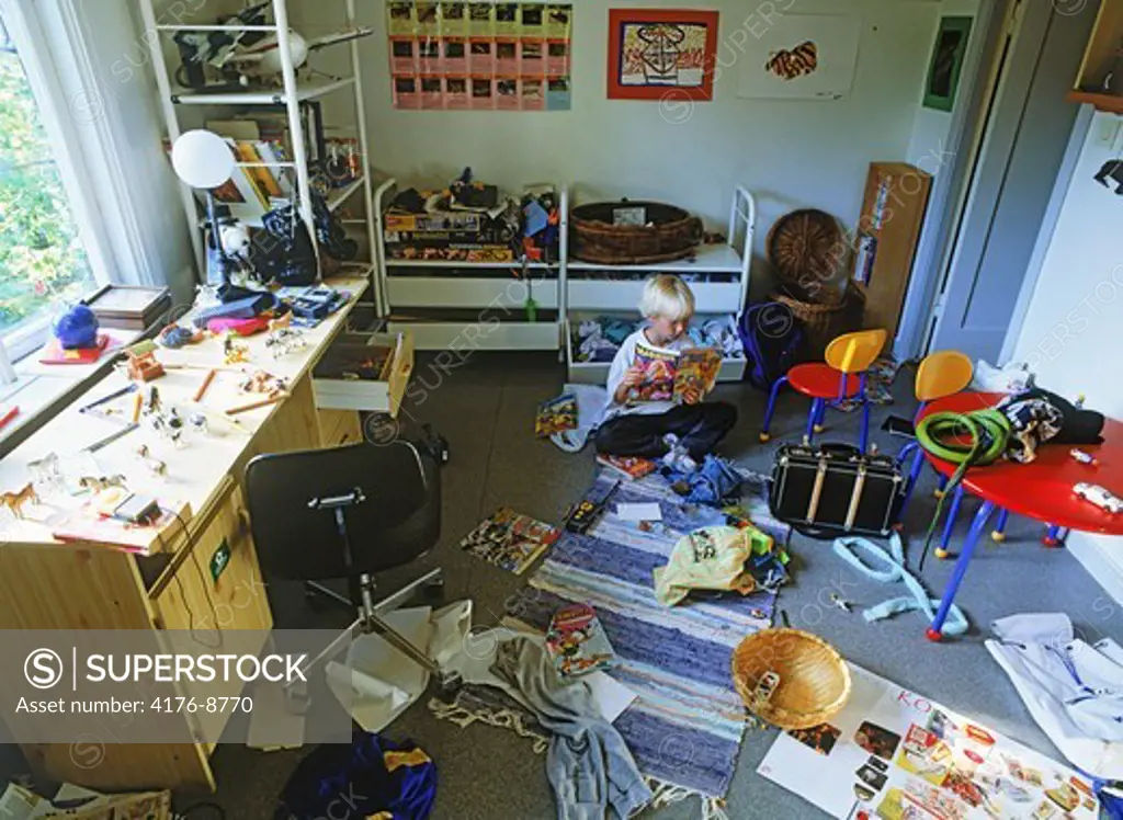Young boy in bedroom amid messy sea of toys