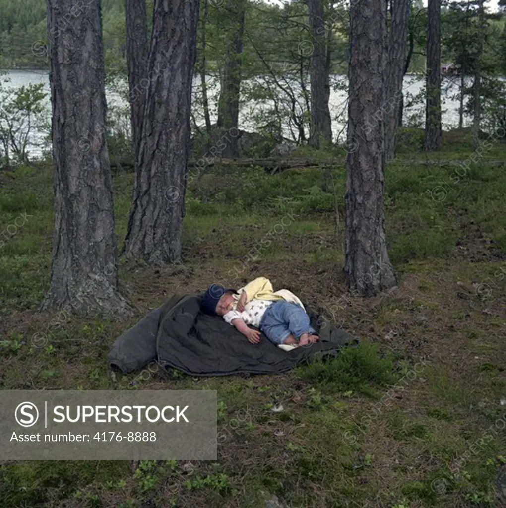 A toddler sleeping in a forest. Sweden