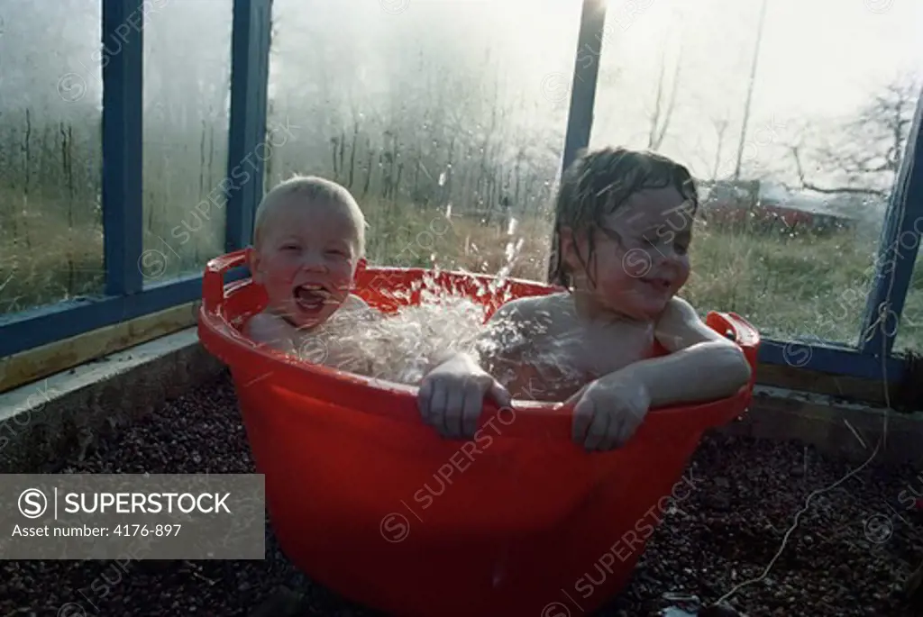 Boy and a girl bathing in a washing tub