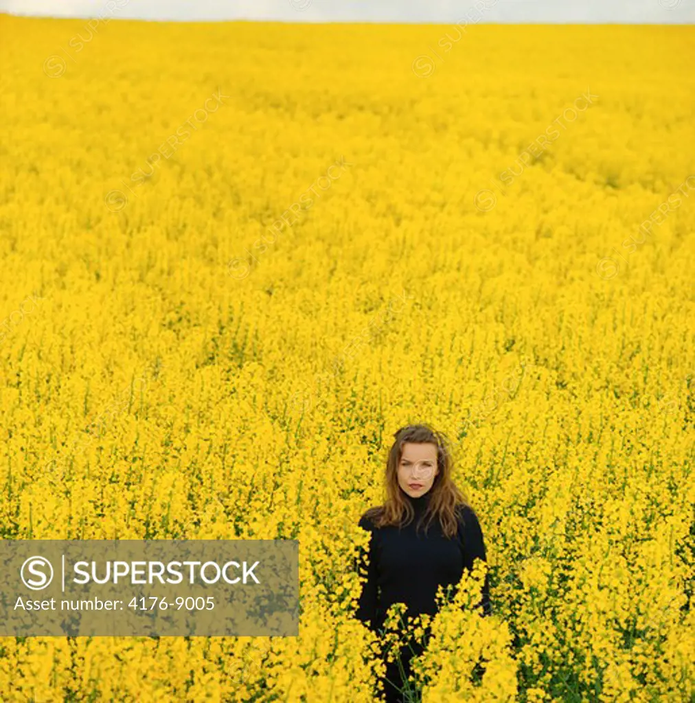 Portrait of a young woman standing in an Oilseed Rape field