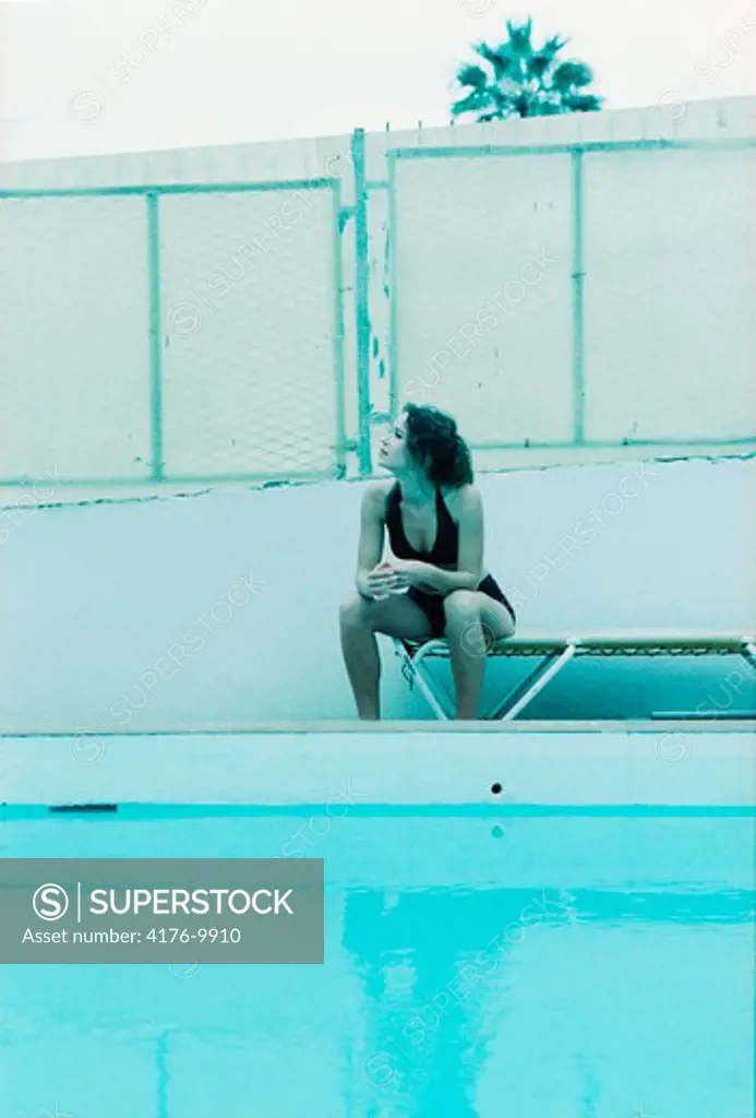 A woman sitting by the swimming pool
