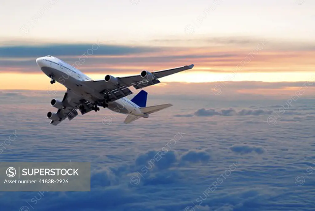 Big passenger airplane flying above the clouds and sunset
