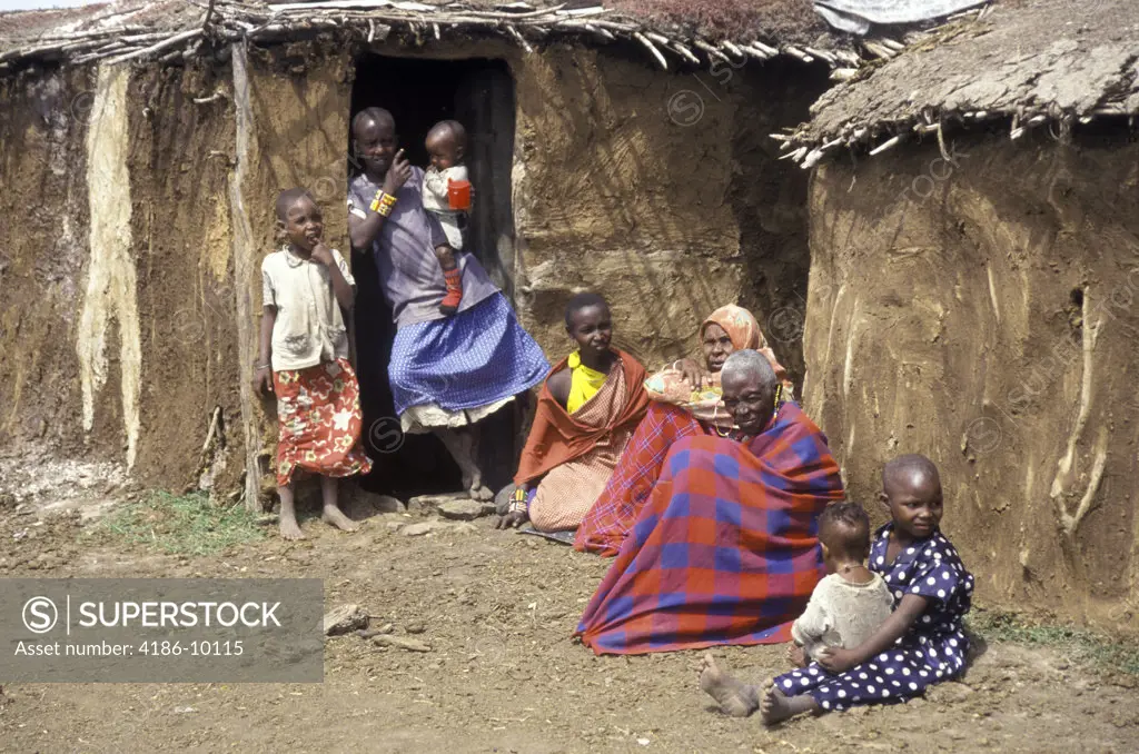 Kenya Masai Women And Children Outside Dung Covered Huts In Masai Mara Village