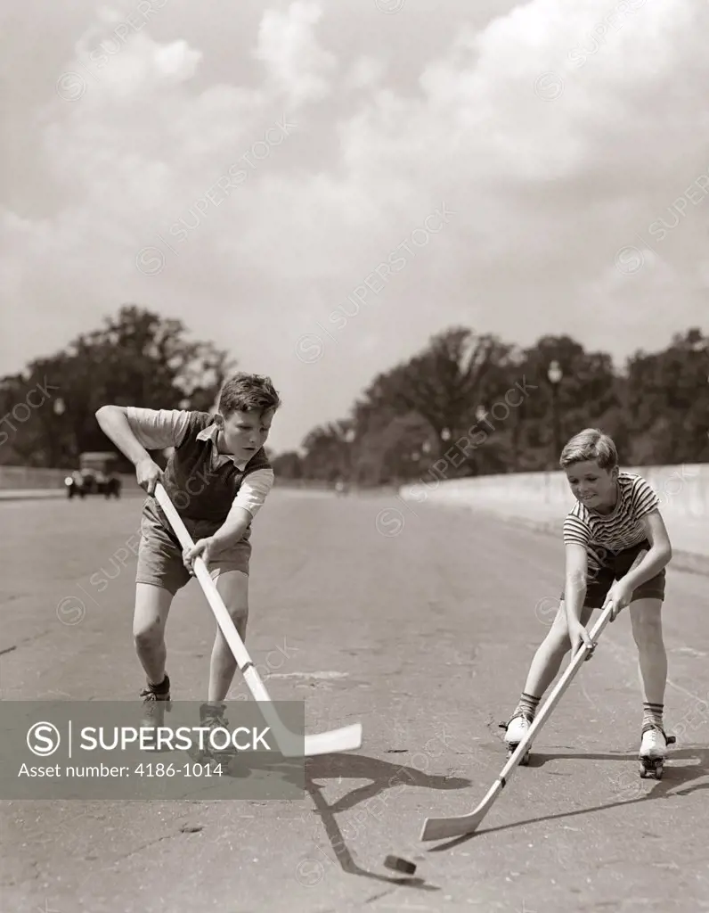 1930S 1940S 2 Boys With Sticks And Puck Wearing Roller Skates Playing Street Hockey