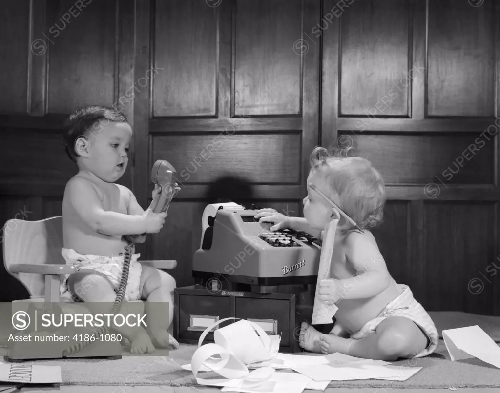 1960S 2 Babies In Diapers 1 On Potty Chair With Telephone Other On Floor With Adding Machine Pencil Behind Ear