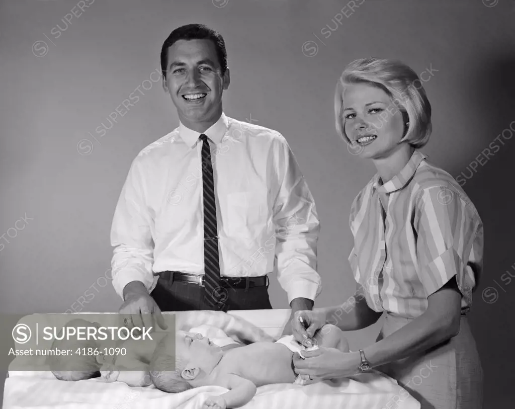 1960S Mother And Father With Twin Babies On Changing Table Smiling Indoor