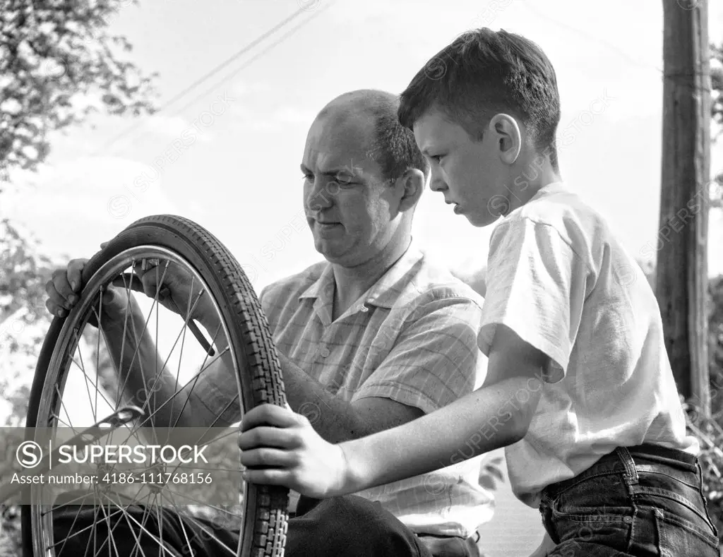 1950s 1960s FATHER AND SON FIXING TIRE ON BICYCLE
