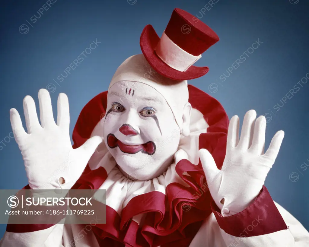 1970s SMILING PORTRAIT OF CLOWN LOOKING AT CAMERA WEARING TINY TOP HAT HOLDING UP HAPPY HANDS IN WHITE GLOVES