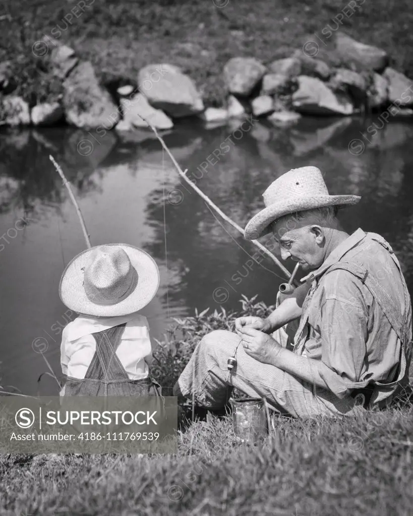 1930s GRANDFATHER AND GRANDSON WEARING STRAW HATS FISHING IN POND