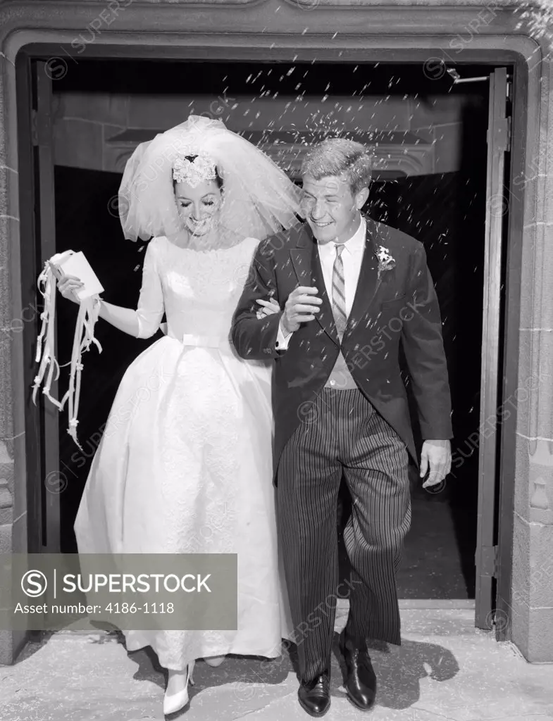 1960S Couple Bride And Groom Arm In Arm Leaving Church Under Shower Of Rice
